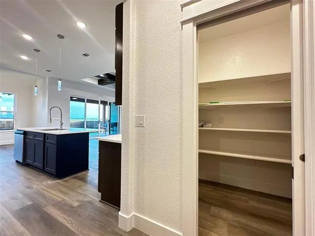 a kitchen with a sink wooden floor and stainless steel appliances