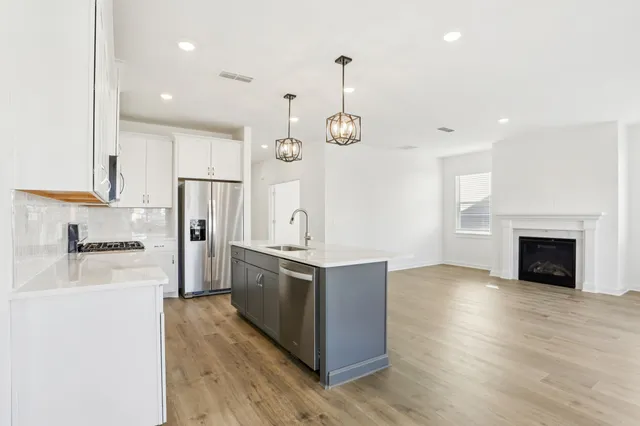 a kitchen with stainless steel appliances granite countertop a refrigerator a stove and a wooden floor