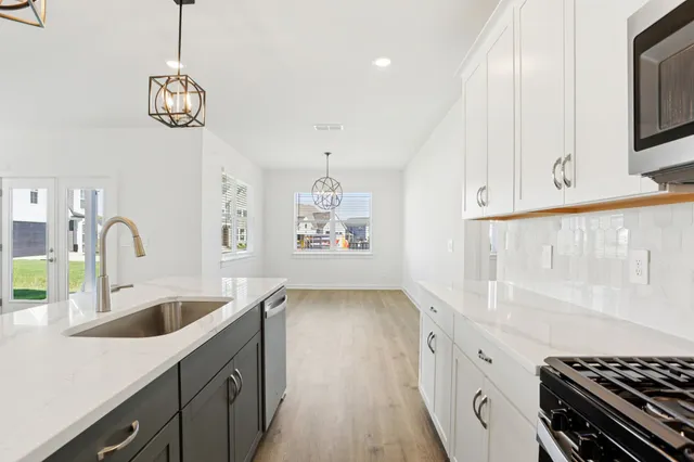 a kitchen with stainless steel appliances granite countertop a sink a stove and a wooden floors