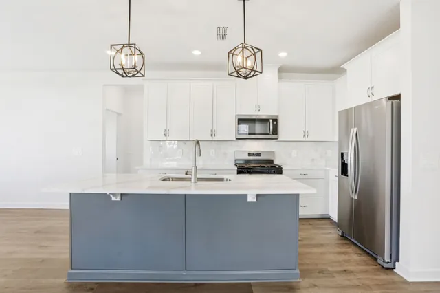 a kitchen with kitchen island white cabinets a refrigerator a stove a sink and dishwasher