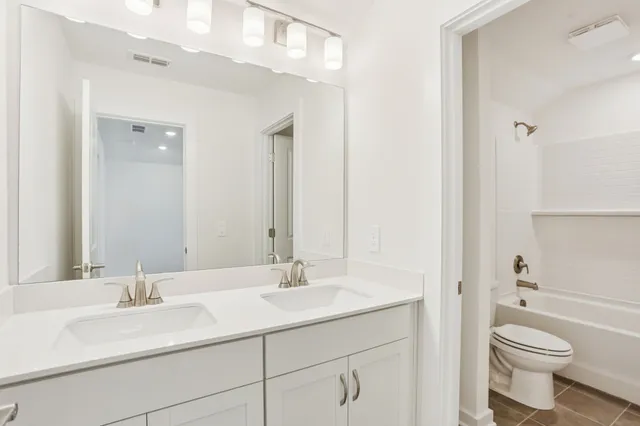 a bathroom with a sink a toilet a mirror and shower