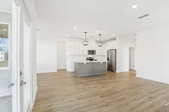 a view of kitchen with kitchen island white cabinets and stainless steel appliances