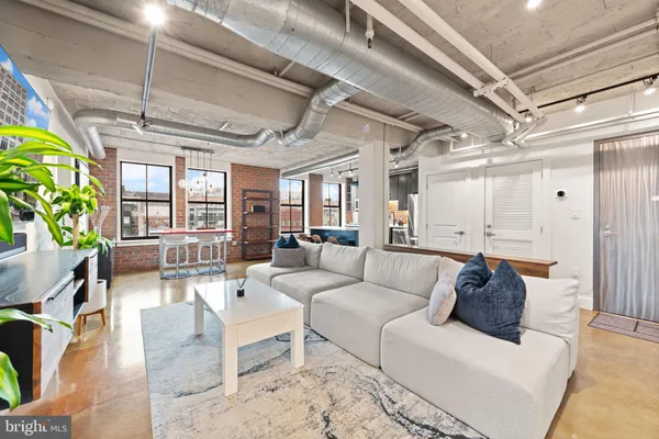 a living room with furniture kitchen view and a chandelier