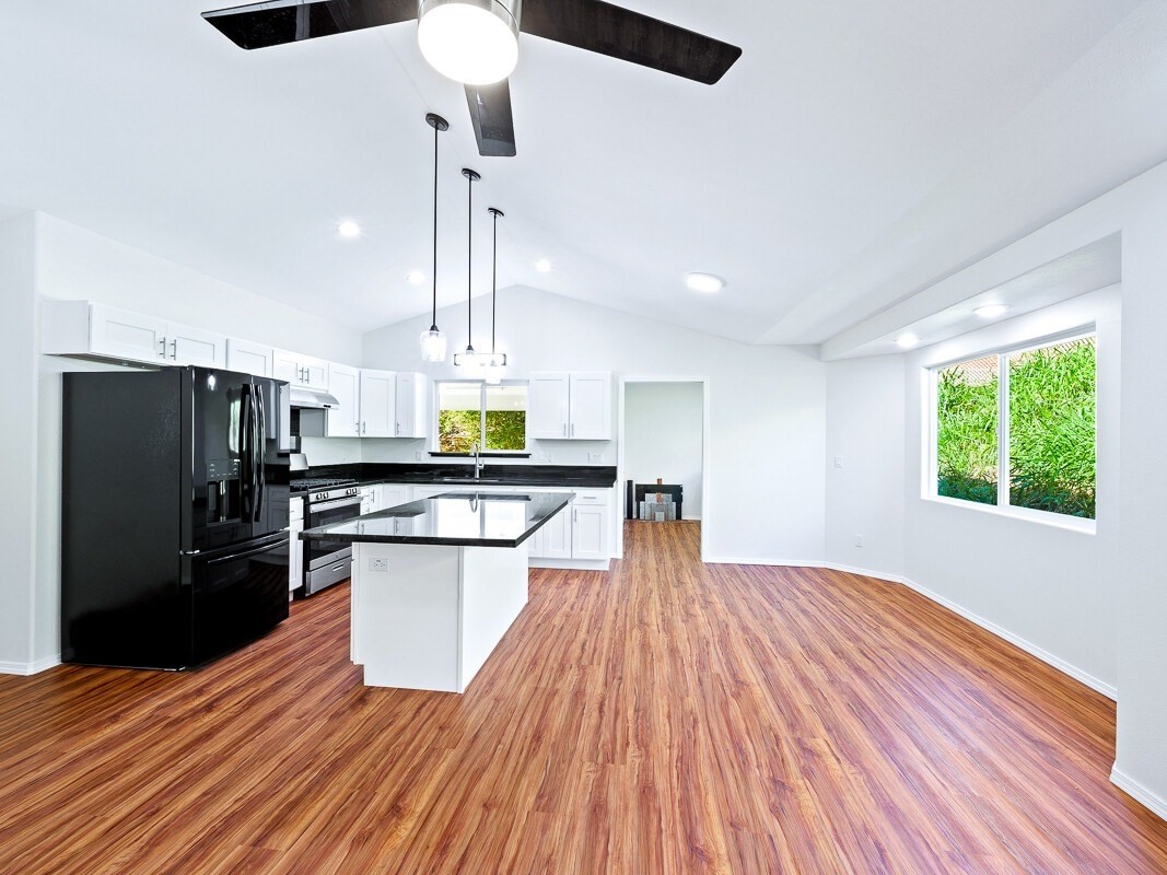 Peleke Road Mountain View, HI 96771 - Photo 8 of 24 a kitchen with stainless steel appliances kitchen island granite countertop a refrigerator a sink dishwasher a stove and a dining table with wooden floor