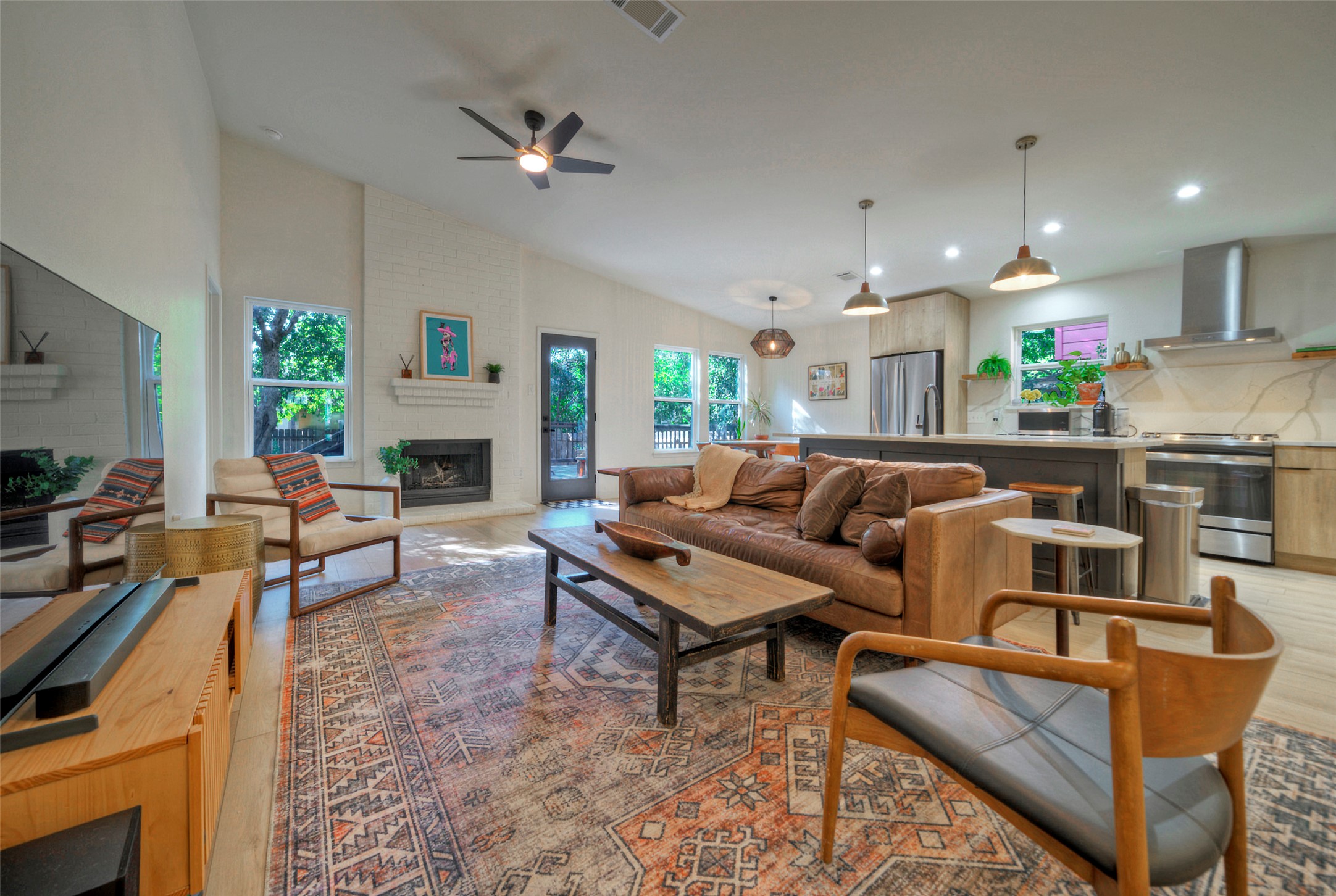 8406 Los Ranchos Drive Austin, TX 78749 - Photo 12 of 32 An open concept living area boasts a fireplace, vaulted ceilings, and a well-appointed kitchen.