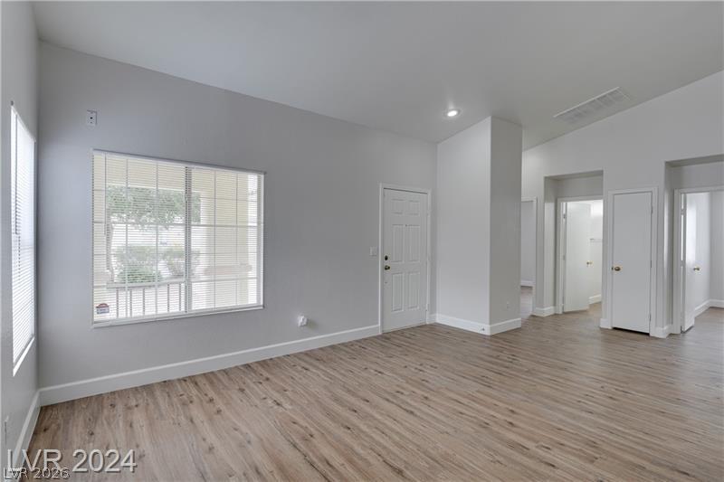 9660 Crystal Ridge Road Las Vegas, NV 89123 - Photo 4 of 18 A versatile living space with light wood-style flooring and high vaulted ceilings offers a blank canvas for personalization.