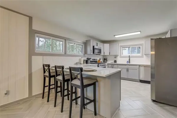 a kitchen with white cabinets and chairs