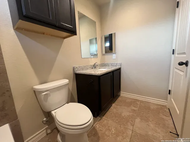 a bathroom with a granite countertop toilet sink and mirror