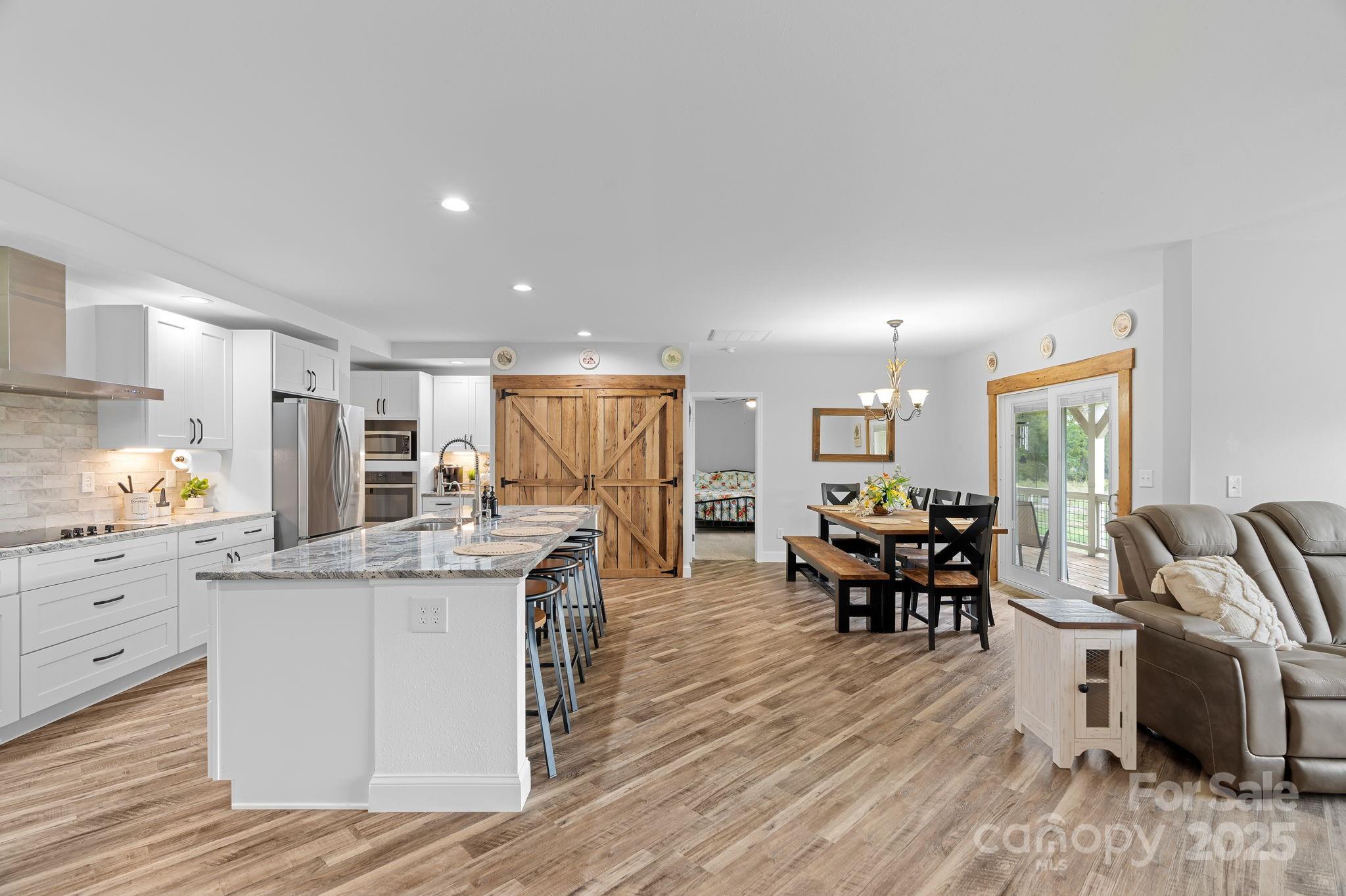 204 Mountain Spring Lane Canton, NC 28716 - Photo 10 of 45 a kitchen with stainless steel appliances kitchen island granite countertop a table chairs stove and white cabinets