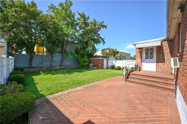 a view of a house with a small yard plants and a large tree