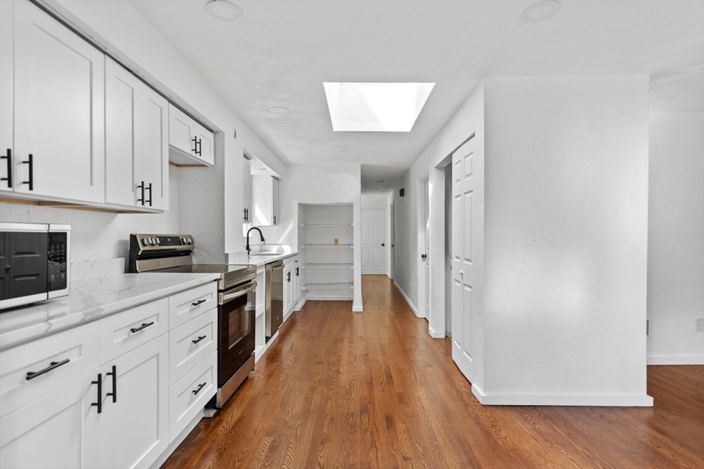 61 Wordsworth Street, Unit 2 Boston, MA 02128 - Photo 2 of 12 a kitchen with white cabinets and wooden floor