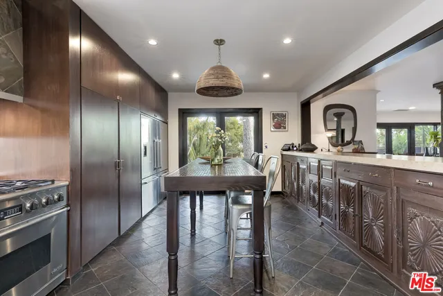 a large kitchen with stainless steel appliances granite countertop a stove a sink dishwasher a dining table and chairs with wooden floor