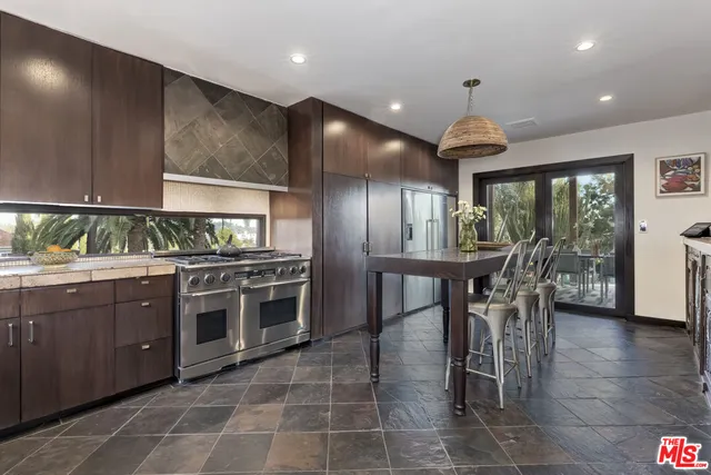 a kitchen with stainless steel appliances granite countertop a stove top oven a sink with dining table and chairs