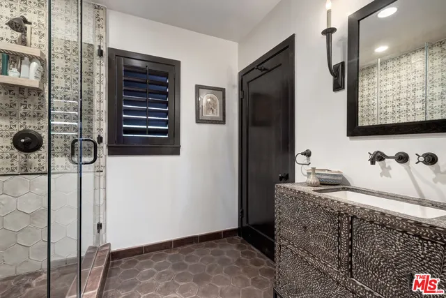 a bathroom with a granite countertop sink a mirror and shower