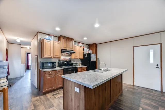 a kitchen with granite countertop kitchen island stainless steel appliances a sink stove and refrigerator