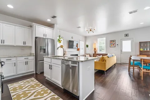 a kitchen that has a lot of white cabinets and stainless steel appliances