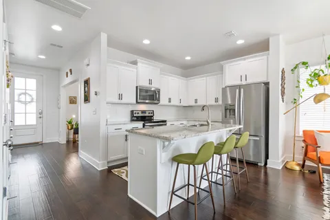 a kitchen with stainless steel appliances a refrigerator a stove a dining table and chairs