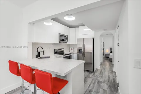 a kitchen with stainless steel appliances granite countertop a sink a stove a refrigerator cabinets and chairs