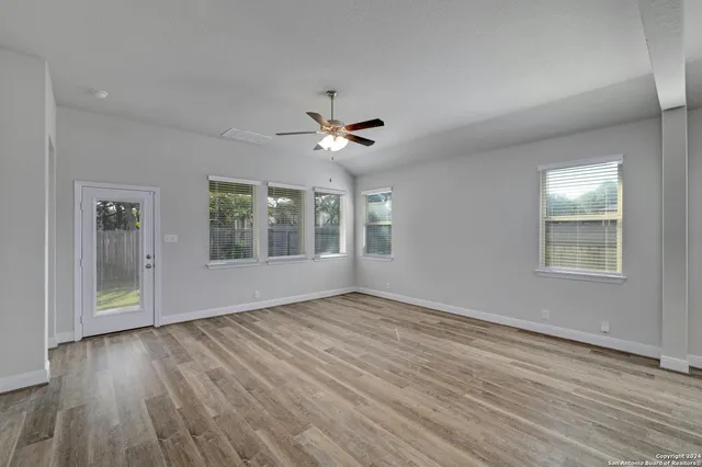 a view of an empty room with a window and wooden floor