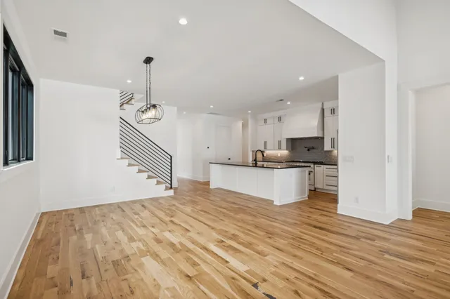 a view of an empty room with wooden floor and a ceiling fan
