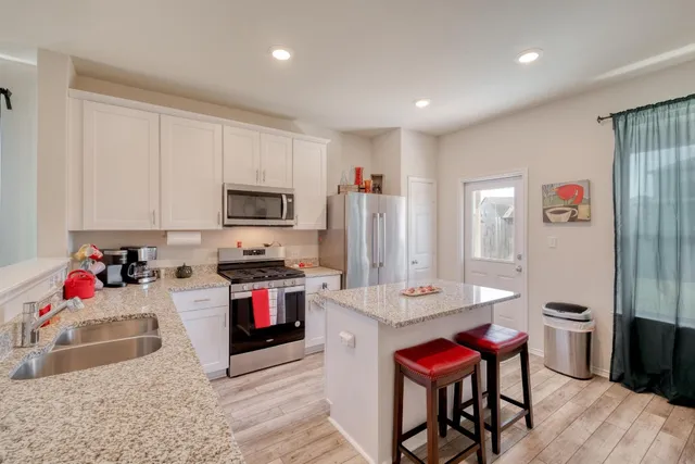 a kitchen with stainless steel appliances granite countertop a stove a sink dishwasher and a refrigerator with wooden floor