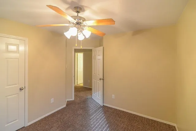 a view of a livingroom with a chandelier fan and windows