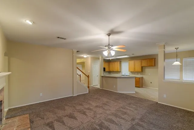 a view of an empty room with window and chandelier fan