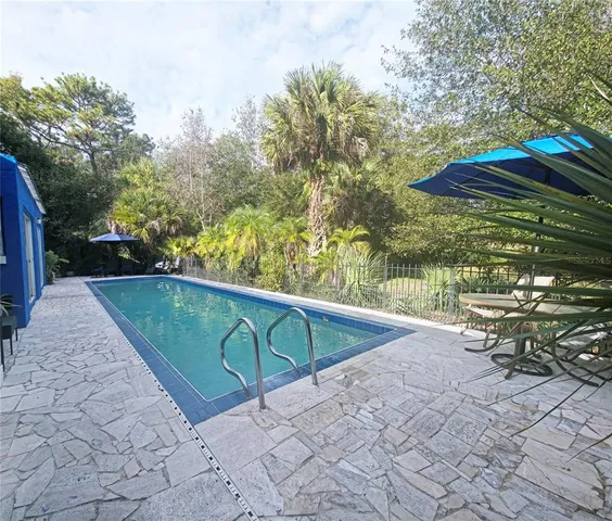 a view of a backyard with lawn chairs under an umbrella