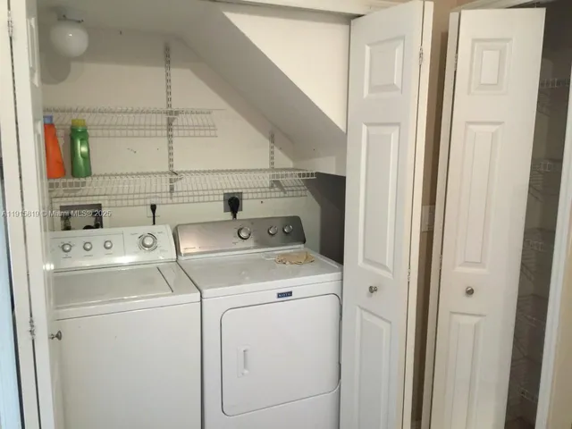 a view of washer and dryer with bathroom in the background