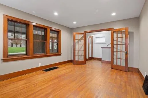 a view of an empty room with wooden floor and a window