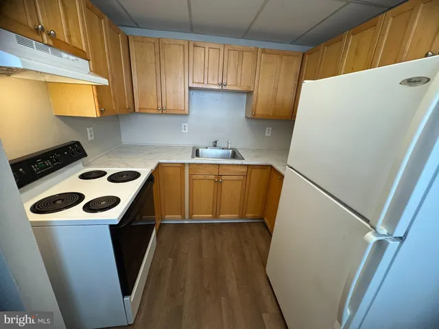 a kitchen with a sink a refrigerator and a stove top oven