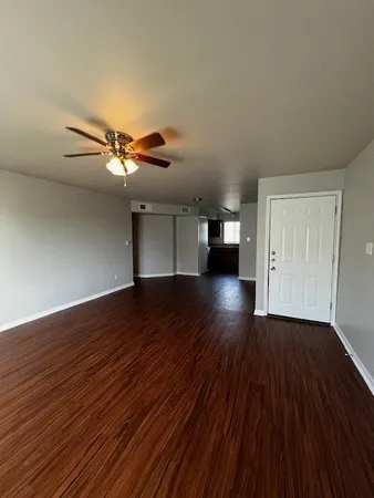 a view of empty room with wooden floor and fan