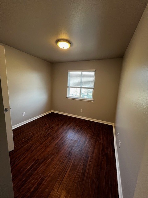 1172 Webberville Road Austin, TX 78721 - Photo 6 of 9 Unfurnished room featuring wood finished floors and a textured ceiling