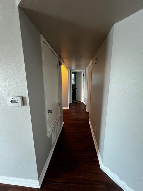 1172 Webberville Road Austin, TX 78721 - Photo 8 of 9 Hallway featuring baseboards and dark wood-style floors