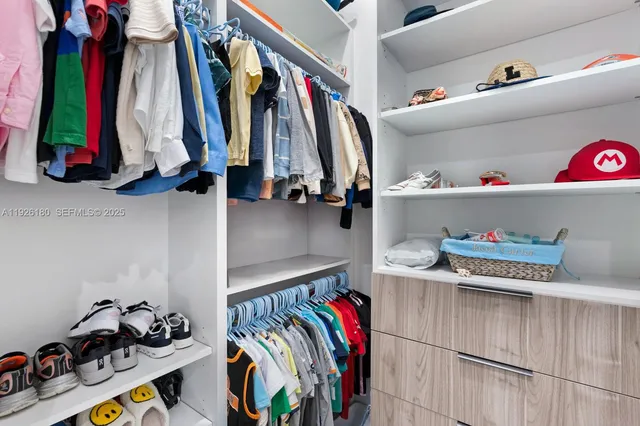 a view of walk in closet with clothes and shoes