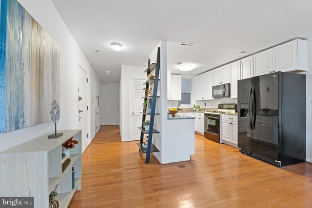 a kitchen with stainless steel appliances a refrigerator and wooden floor