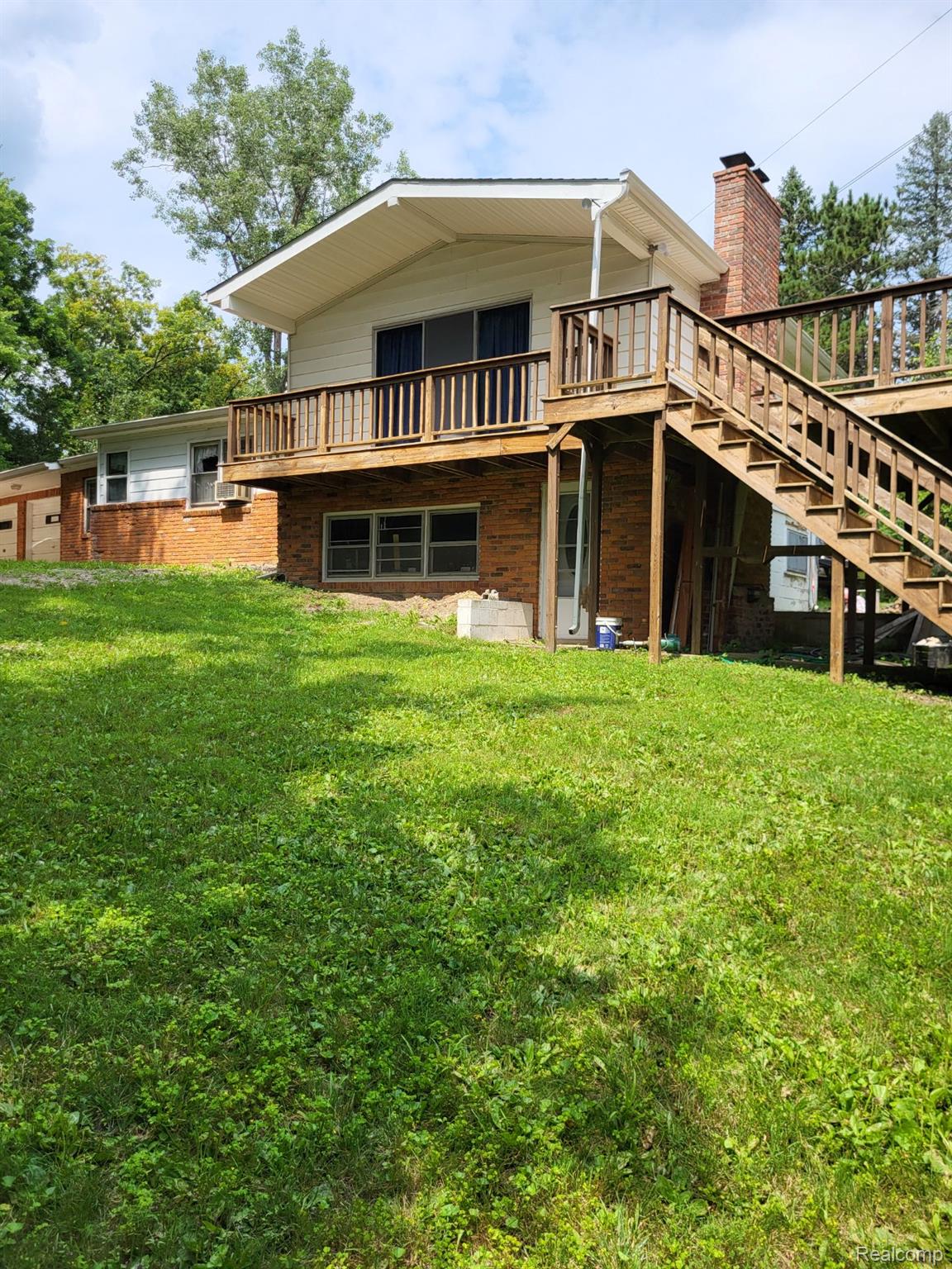 4662 North Lapeer Road Columbiaville, MI 48421 - Photo 2 of 19 Rear view of house with stairway, brick siding, a yard, a chimney, and a balcony