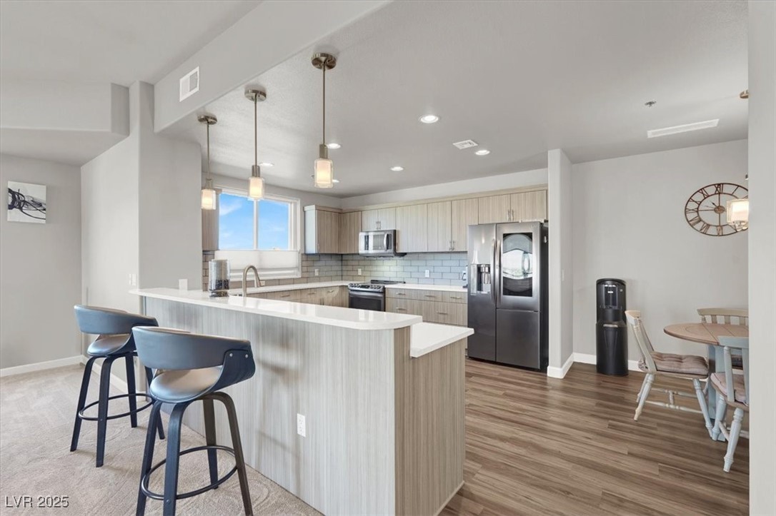 8255 South Las Vegas Boulevard, Unit 722 Las Vegas, NV 89123 - Photo 3 of 40 Kitchen with stainless steel appliances, a peninsula, a kitchen breakfast bar, light countertops, and decorative backsplash