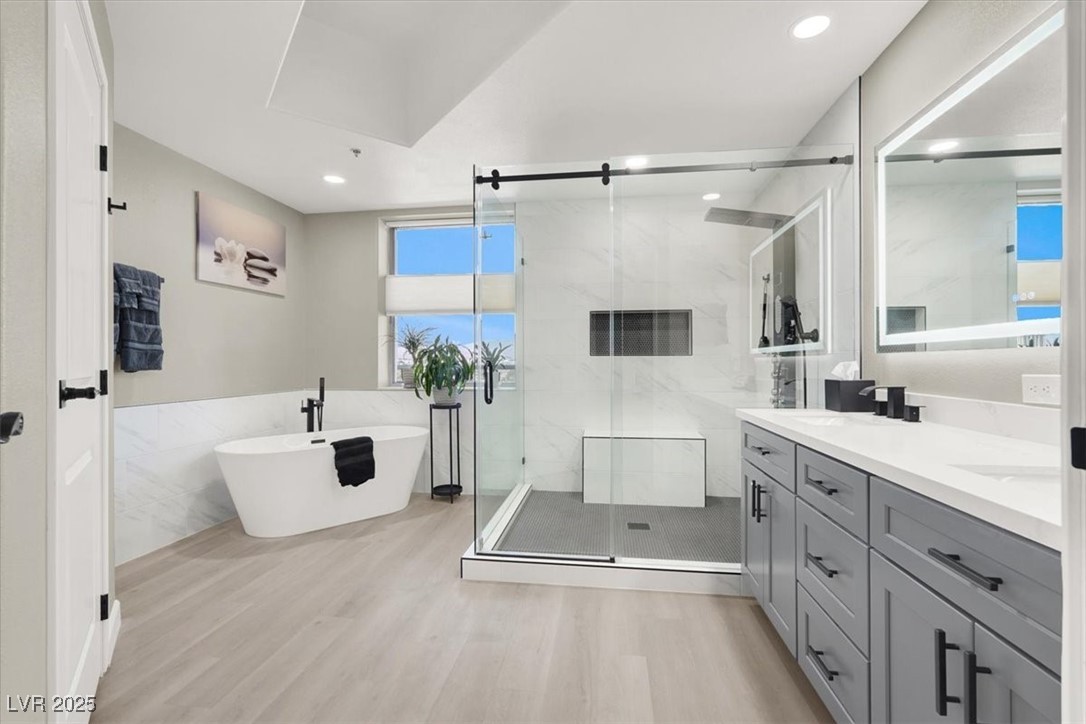8255 South Las Vegas Boulevard, Unit 722 Las Vegas, NV 89123 - Photo 29 of 40 Bathroom with double vanity, wood finished floors, a soaking tub, a marble finish shower, and recessed lighting