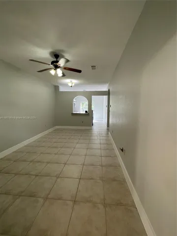 a view of an empty room with a chandelier fan and a window