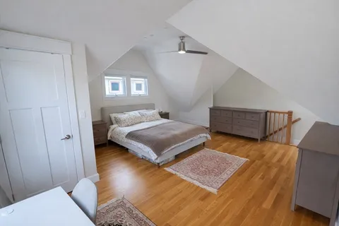 a bedroom with a bed and a night stand with wooden floor