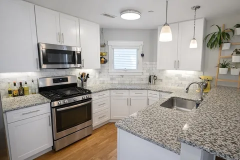 a kitchen with stainless steel appliances granite countertop a sink stove and microwave