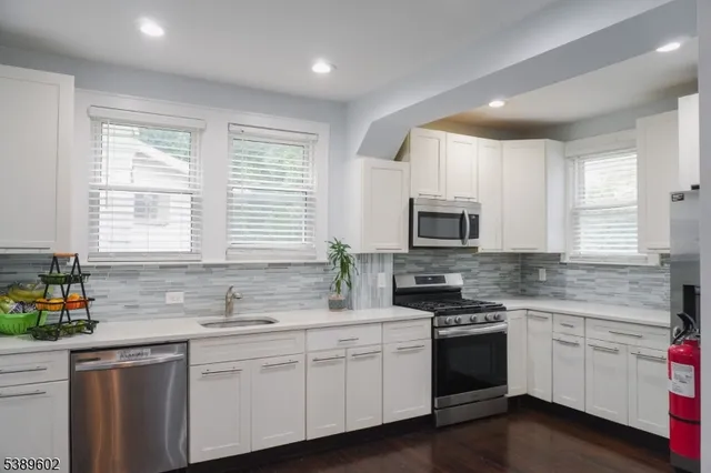 a kitchen with granite countertop white cabinets white appliances a sink and a window