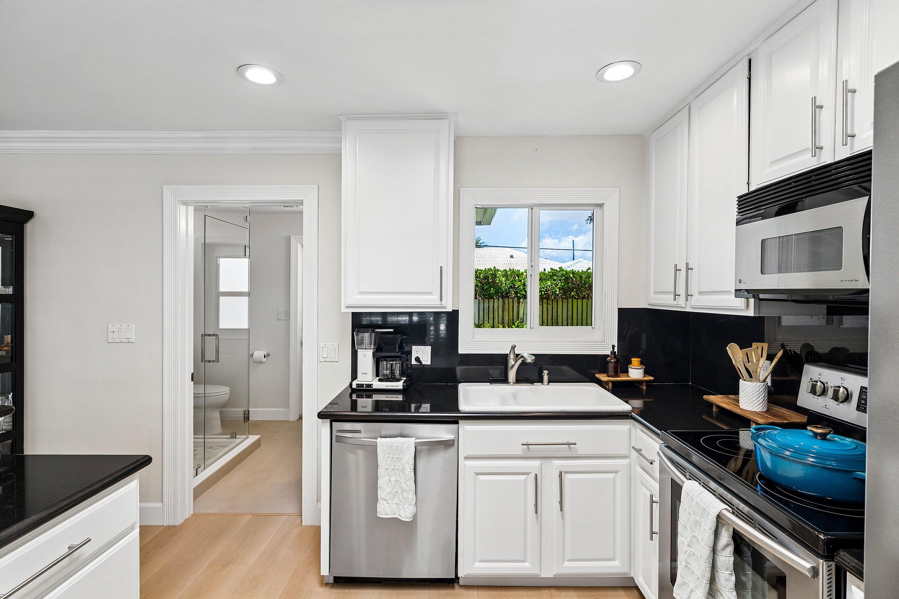 774 Southwest 7th Street Boca Raton, FL 33486 - Photo 13 of 28 a kitchen with granite countertop a stove a sink and a microwave