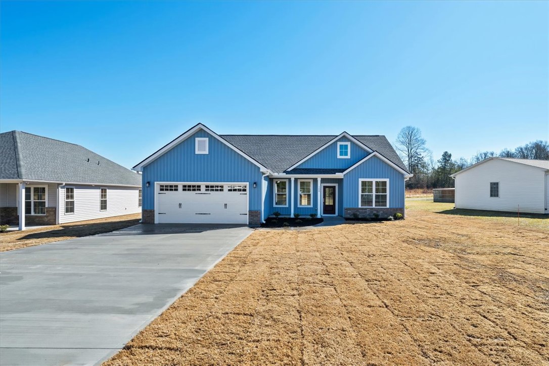 This newly constructed home features a crisp blue exterior and an inviting driveway.