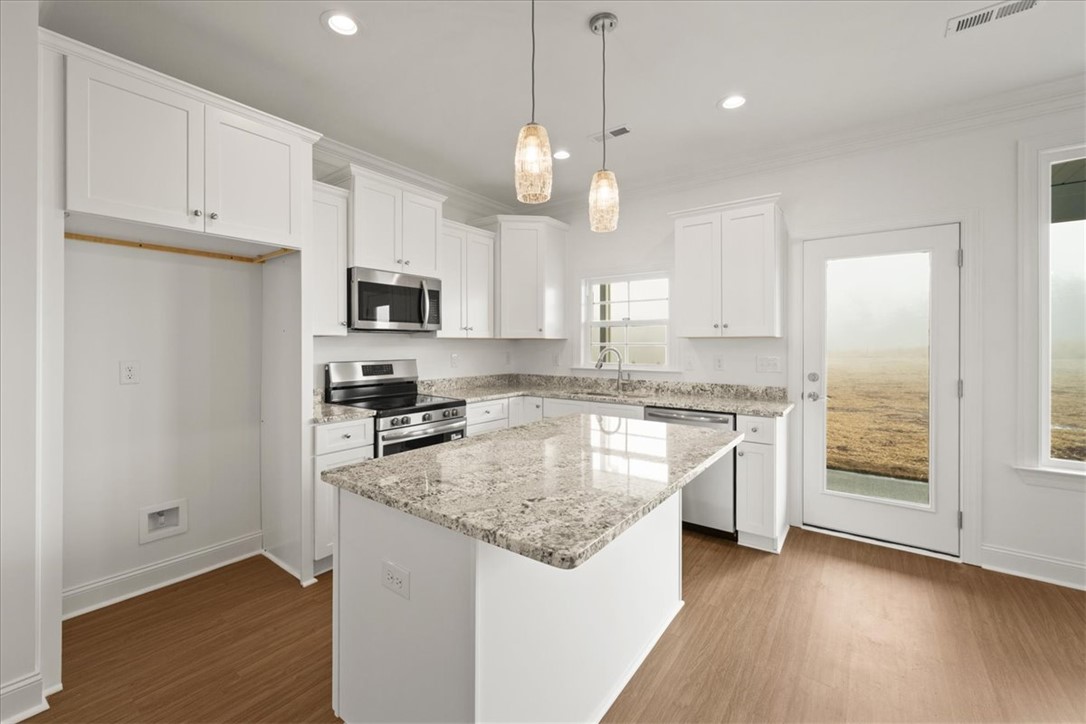 108 Oak Grove Road Norris, SC 29667 - Photo 11 of 35 This modern kitchen features elegant countertops, an island, and a door leading to the outside.