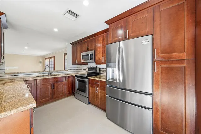 a kitchen with stainless steel appliances granite countertop a refrigerator and a sink