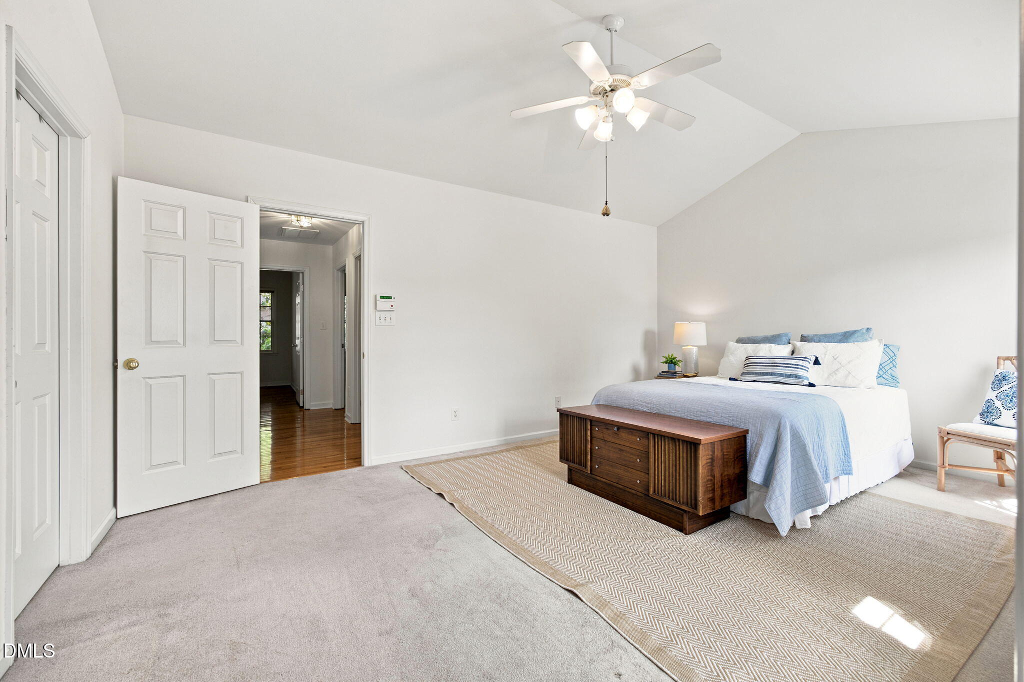 8211 Hempshire Place, Unit 104 Raleigh, NC 27613 - Photo 18 of 34 Spacious room featuring a vaulted ceiling with a ceiling fan, light-colored carpeting, and a doorway opening to wood-finish flooring