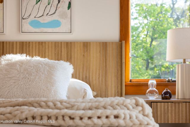 a bedroom with a bed and a large mirror next to a window