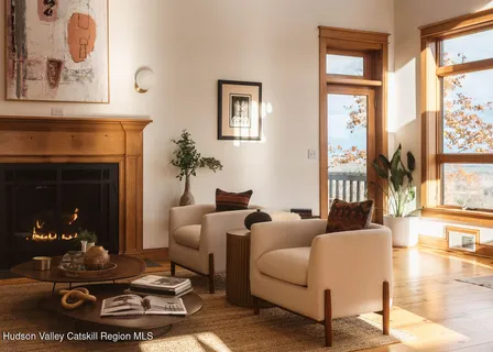 a living room with furniture a fireplace and floor to ceiling windows